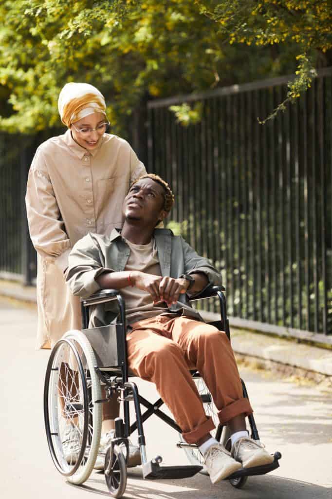 personne qui aide un handicapé à le pousser dans une chaise roulante